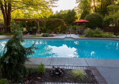 pool with stamped concrete patio, seating wall and pergola