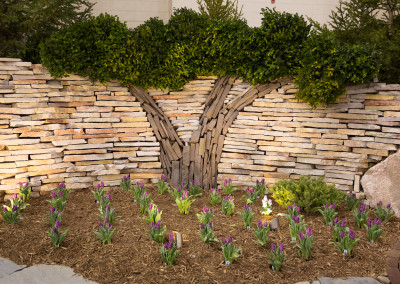 custom stone wall topped with boxwood designed to look like a tree