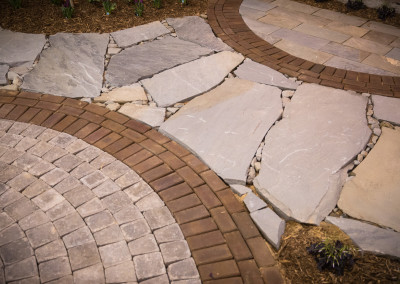 a mix of natural stone and brick pavers set in a decorative patio