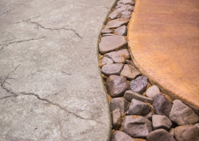 river of rocks in between stamped, stained concrete slabs