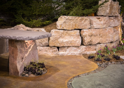 stone retaining wall with concrete counter and outdoor lighting