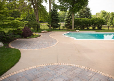 inground pool surrounded by concrete slab and slate pavers