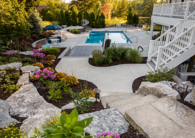 long view of landscaped backyard with built in pool and hot tub