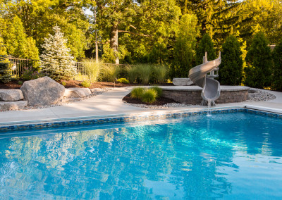 underground pool with water slide and seating wall