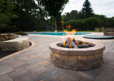 built in gas fireplace in front of an inground pool