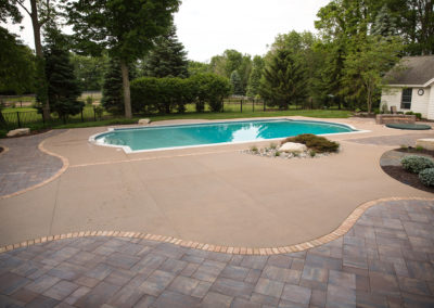 inground pool surrounded by concrete slab and slate pavers