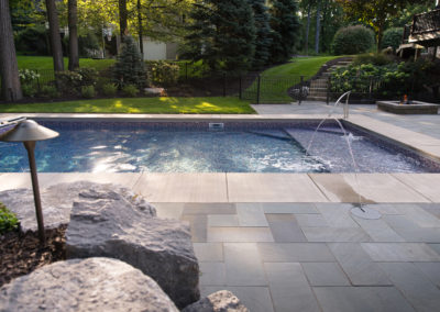 pool with blue stone patio and water jets